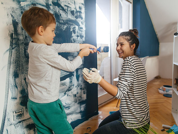 Young boy and woman painting room